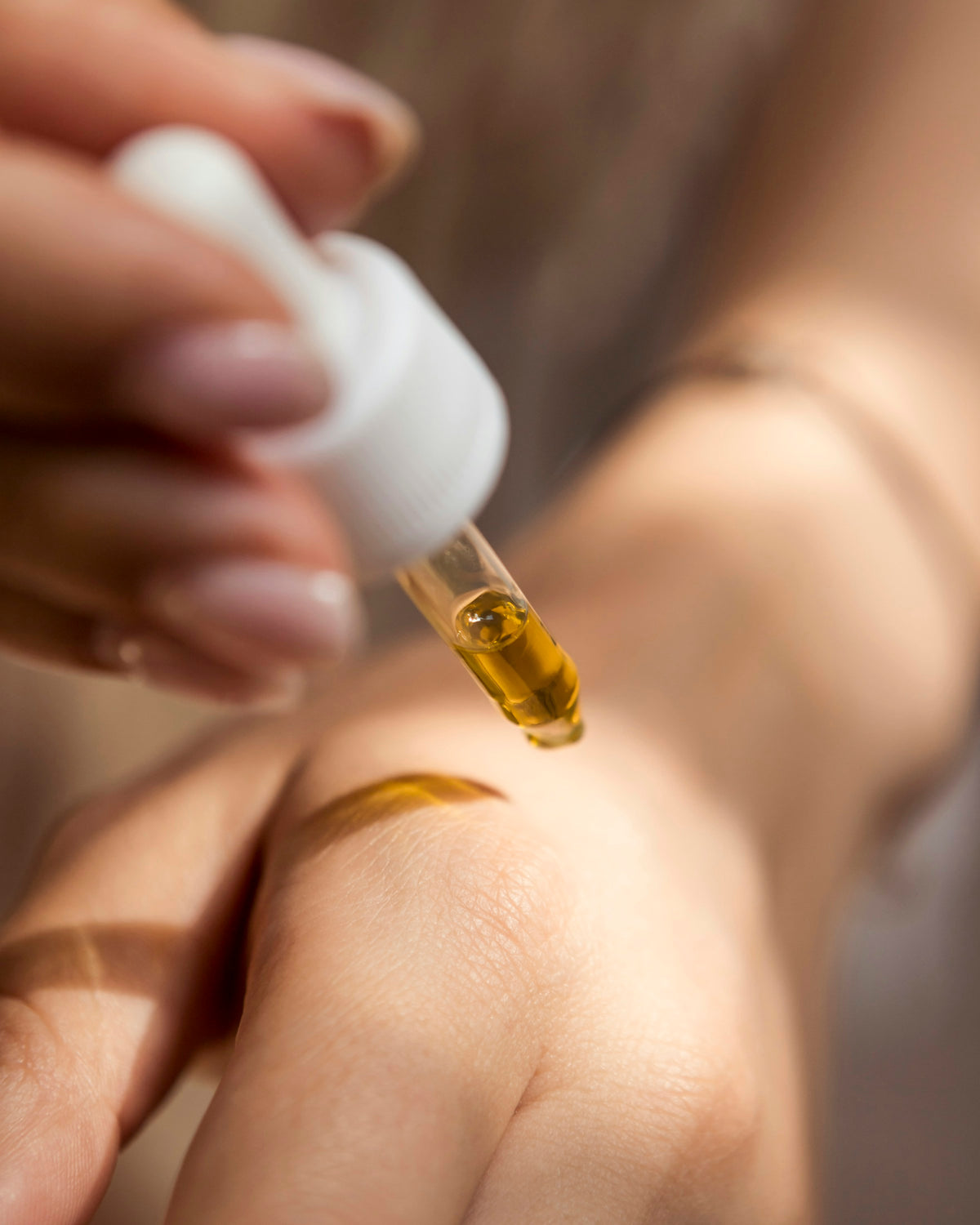 Serum dropper over skin in warm light