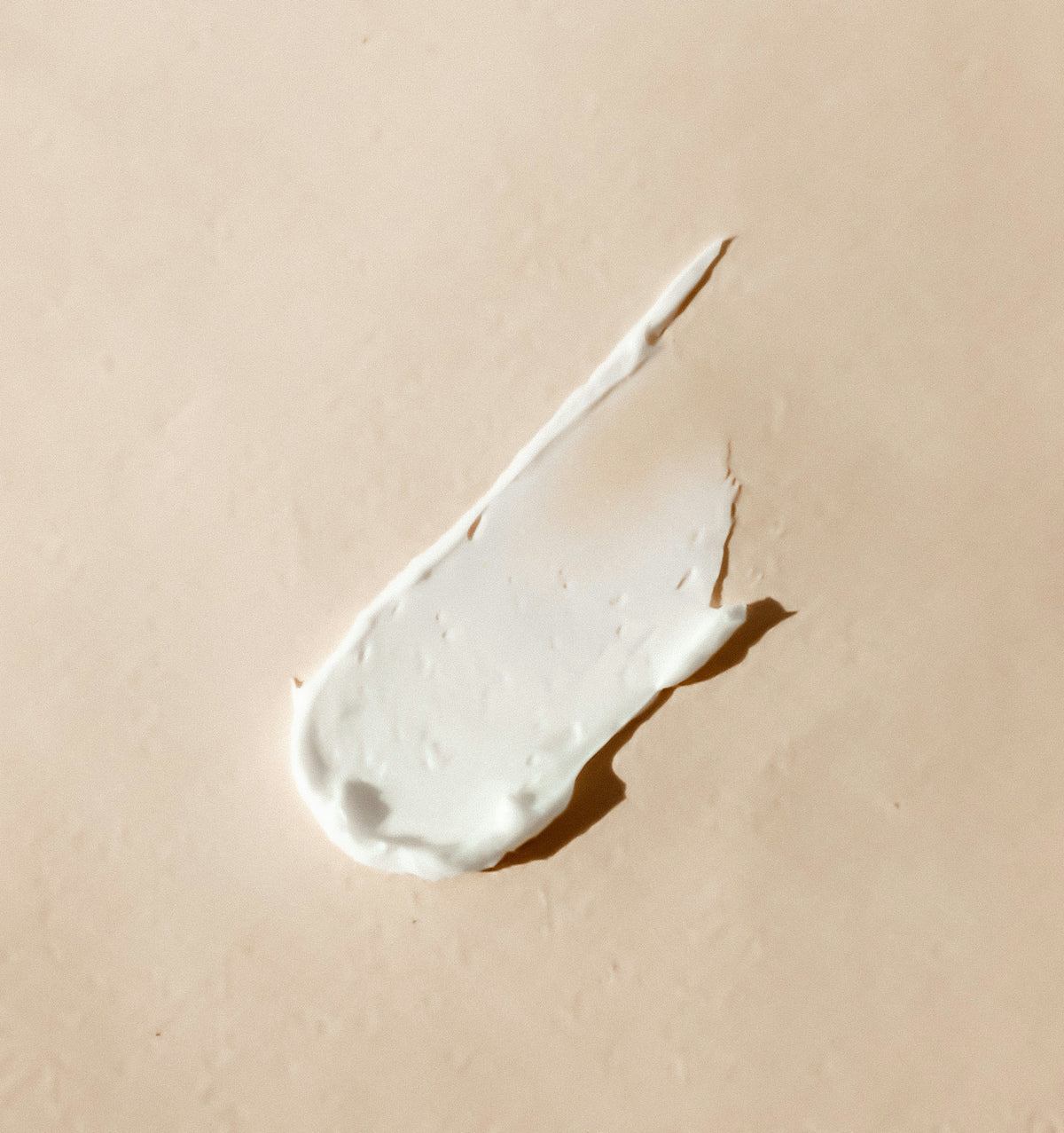 Cream texture swatch on a beige surface