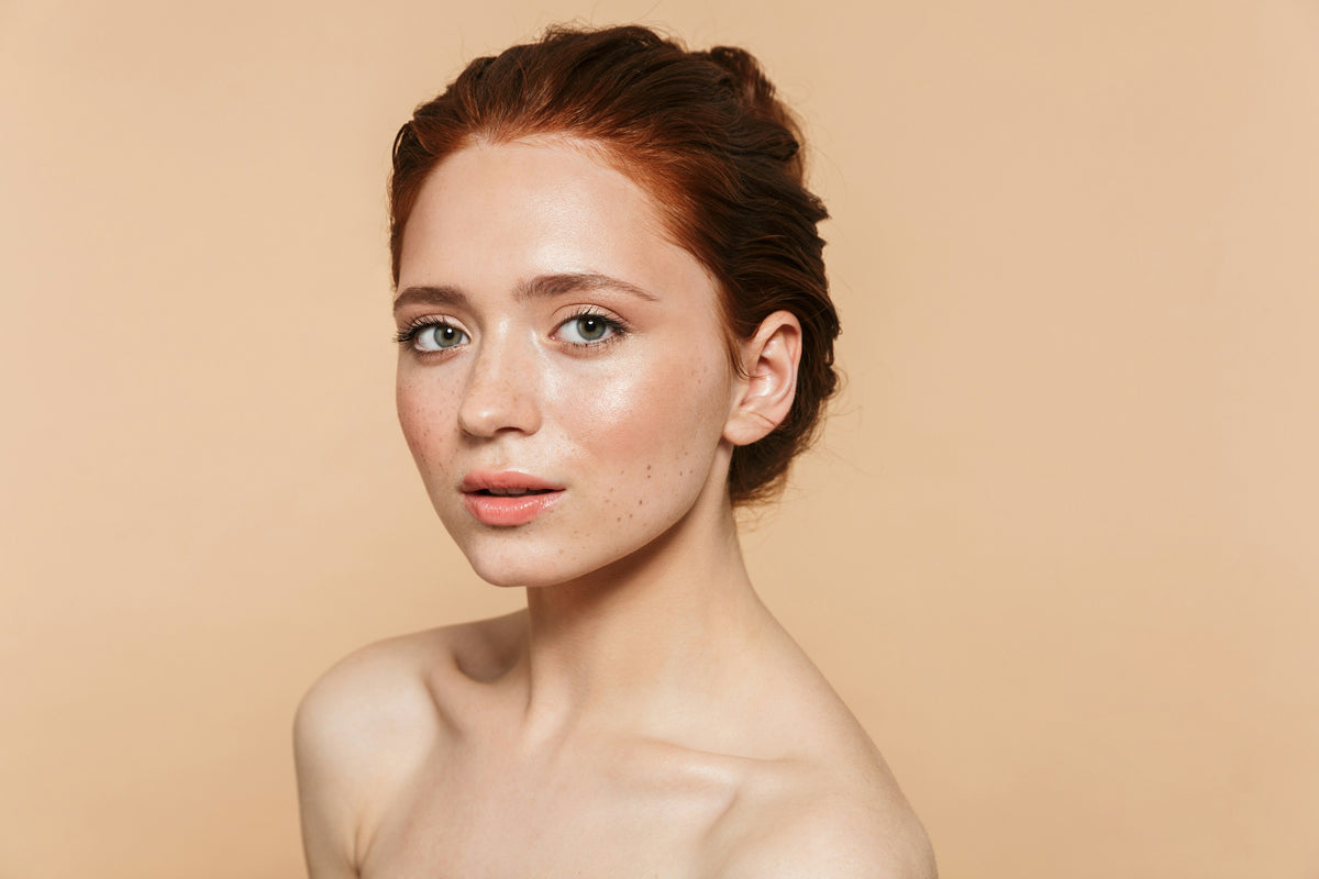 Woman with natural freckled skin on a warm peach background